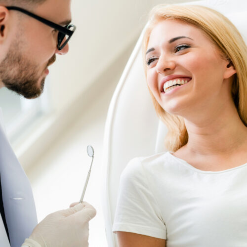 Young Dentist Talks With Patient In Dental Clinic